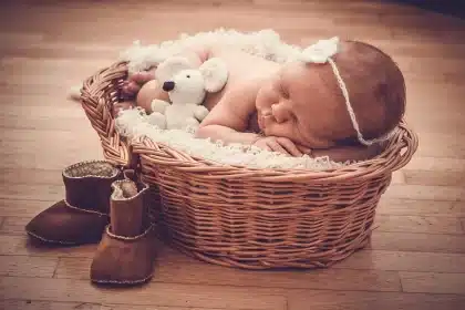 Nursery shelf with folded organic baby blankets and unlabeled baby-care bottles on a wooden dresser