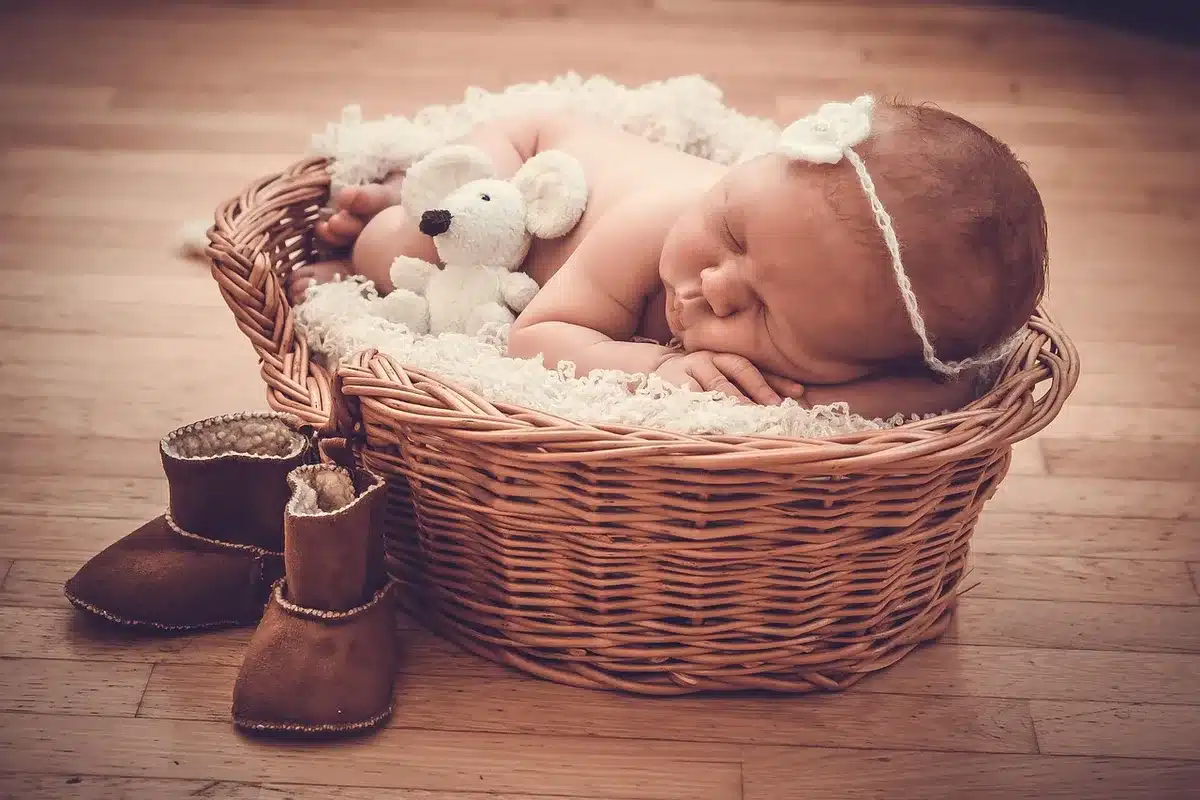 Nursery shelf with folded organic baby blankets and unlabeled baby-care bottles on a wooden dresser