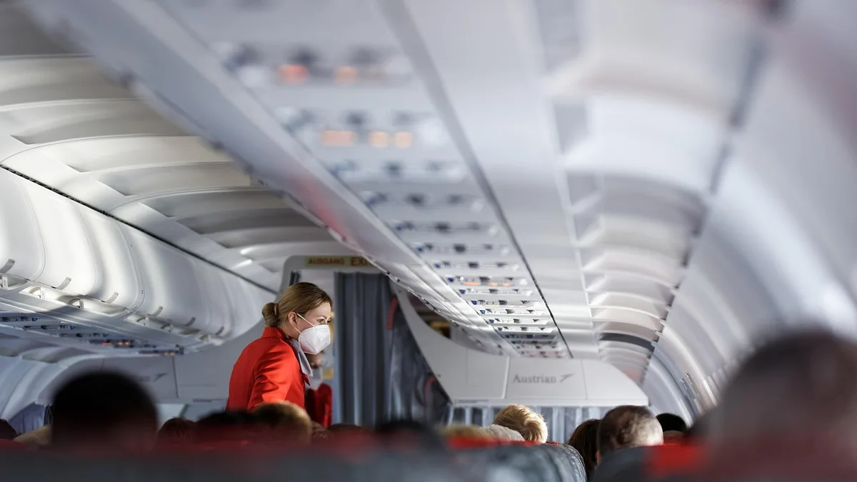 Inside an airplane cabin showing passengers and seating rows
