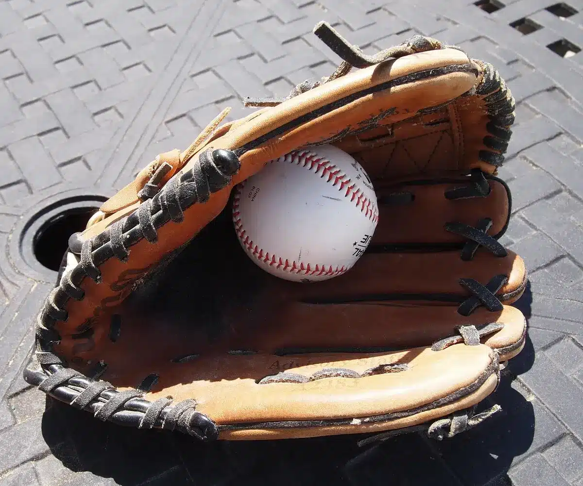 Dugout bench with catcher gear and a notebook, scoreboard blurred in background
