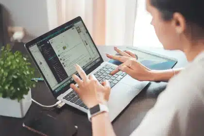 Hands holding a smartphone with a loyalty account dashboard and a laptop nearby